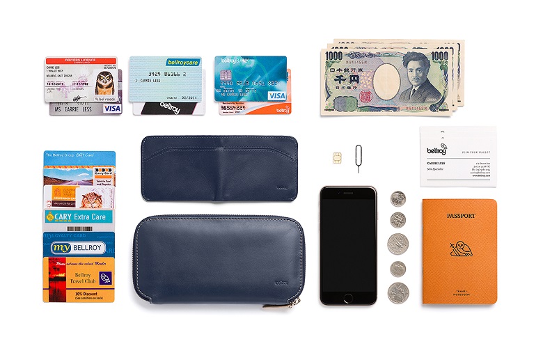 bellroy carry out wallet blue steelに収納できる貴重品の参考としてスマートフォン、小銭、パスポート、SIMカード、SIMピン、名刺、カード類、紙幣を並べた様子
