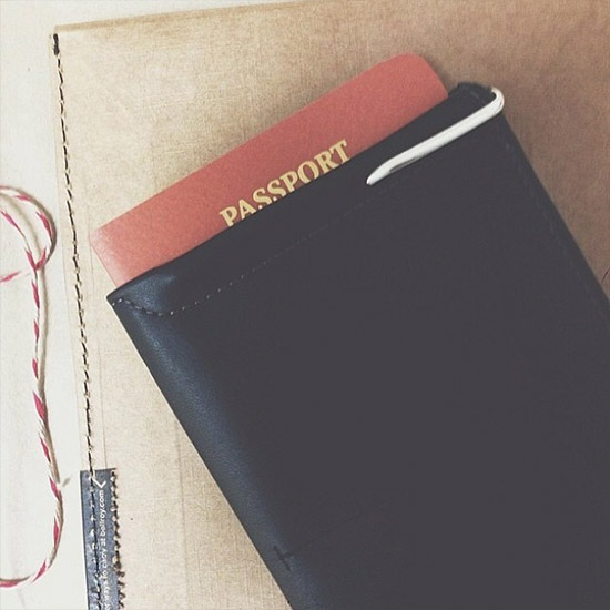 オリジナルパッケージの上に置かれたパスポートスリーブブラックのメインポケットにパスポートを収納したイメージ