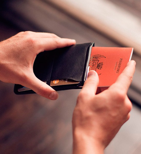 クレジットカードが2枚収納されたパスポートスリーブブラックにパスポートを収納する写真