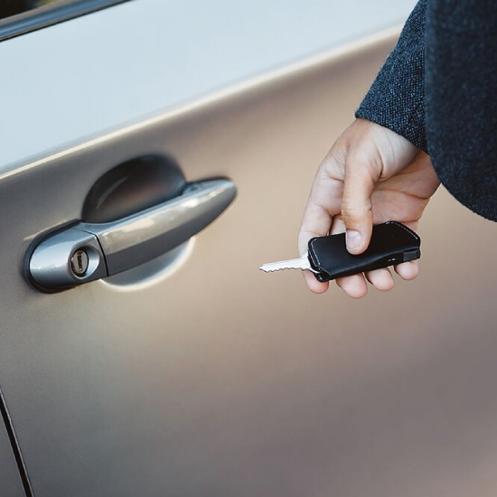 キーカバーブラックの中の鍵を一本だけ反転させて車の鍵を開けようとしている男性の写真