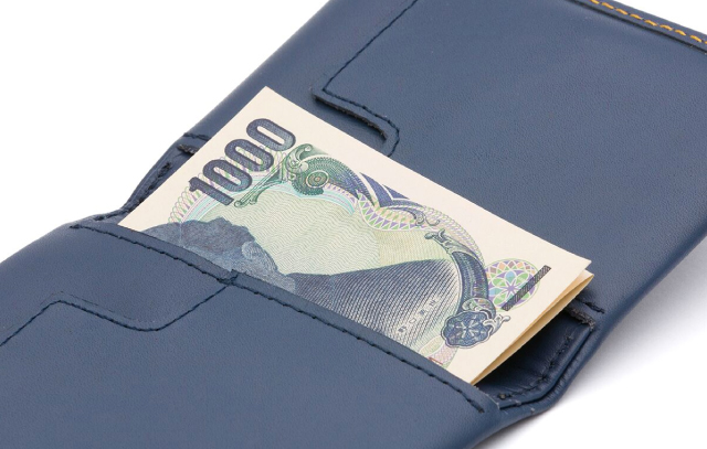 スリムスリーブウォレットバーントオレンジの左ポケットに千円札を折りたたんで収納しているイメージ
