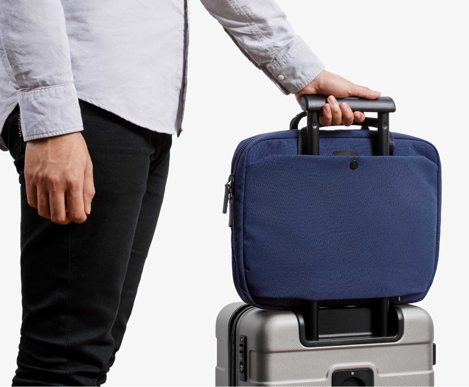 ベルロイラップトップブリーフ　インクブルーをスーツケースのハンドルに設置し、それを持つ男性の画像